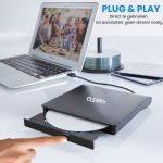 Zwarte Clerby externe DVD-speler aangesloten op een laptop, met een uitgeschoven lade waar een hand op drukt.