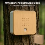 Vierkante witte en houten unit met gaatjes, gemonteerd op een boomstam. Klein bruin kartonnen doosje ernaast. Tekst: Ontspannende natuurgeluiden.