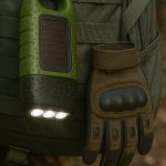 Groene zaklamp met 3 verlichte LED-lampen, bevestigd aan een rugzak naast een handschoen.