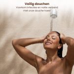 Vrouw geniet van het douchen onder een douchekop, haar haar is nat.