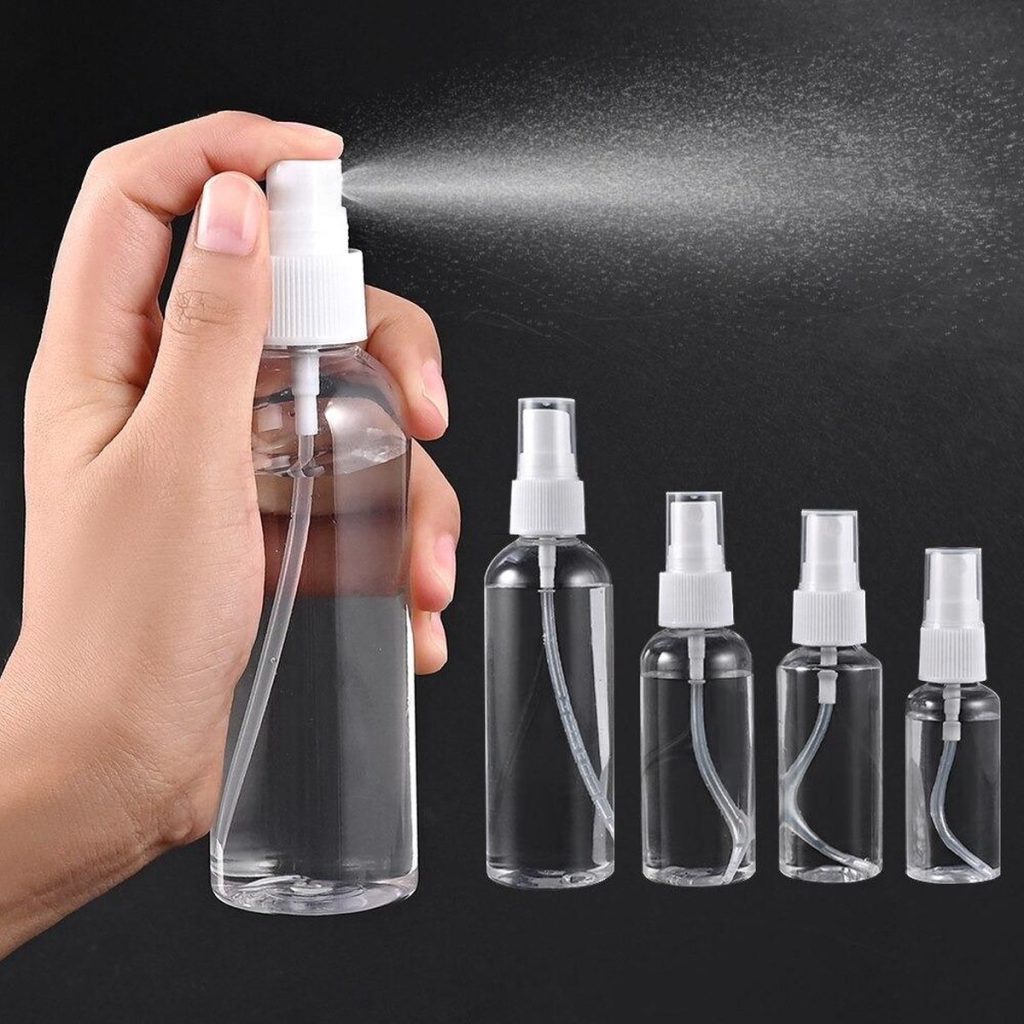 Hand houdt een doorzichtig 50ml sprayflesje vast met witte dop, die een fijne nevel verstuift. Naast staan vier kleinere varianten.