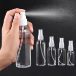 Hand houdt een doorzichtig 50ml sprayflesje vast met witte dop, die een fijne nevel verstuift. Naast staan vier kleinere varianten.