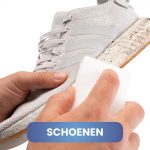 Handen maken een lichte stoffen sportschoen schoon met een witte wonderspons.