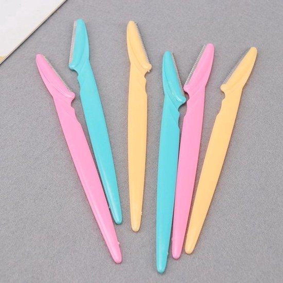 Zes gezichts-scheermesjes in pastelkleuren: roze, turquoise en geel.