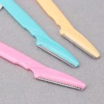 Close-up van roze, turquoise en gele gezichts-scheermesjes met metalen bladen.