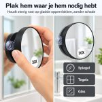 Hand plaatst zwarte 30x vergrootspiegel met zuignap op een spiegel. Geschikt voor spiegel, tegels en glas.